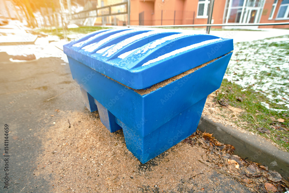 Blue storage grit bin placed for winter sand treatment to reduce slippery sidewalks and icy road hazards, ensuring public safety during cold weather. Grit bin covered with snow Blue storage grit bin placed for winter sand treatment to reduce slippery sidewalks and icy road hazards, ensuring public safety during cold weather. Grit bin covered with snow