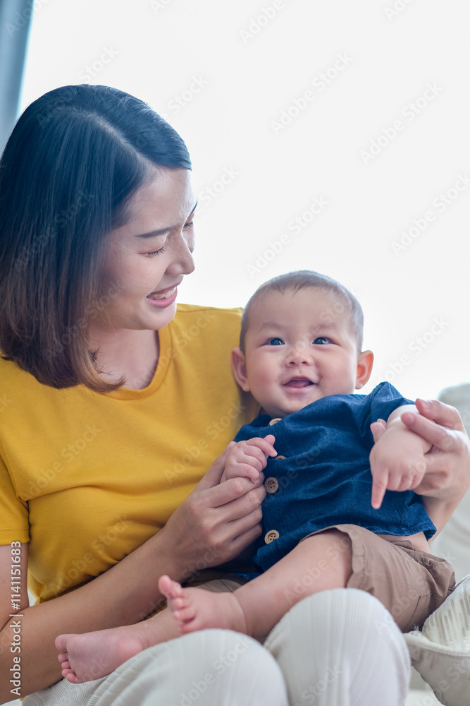 Asian woman with her son holding him by her hand. Happy baby boy was holding by his mother. Asian family with little boy at home enjoy tender family moment, motherhood. Asian woman with her son holding him by her hand. Happy baby boy was holding by his mother. Asian family with little boy at home enjoy tender family moment, motherhood.