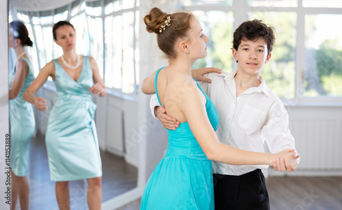 Experienced female dancer teaches tango to pair of teenagers in the ballroom photo