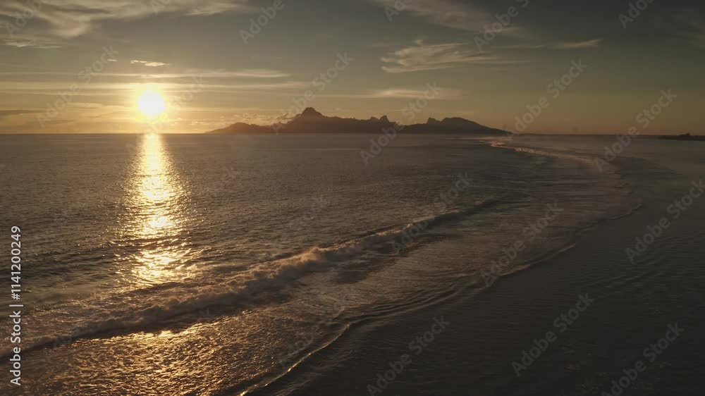 Golden sunset reflecting on calm ocean water with gentle waves splashing coastline sand beach, Moorea tropical island in background create picturesque paradise scene. Remote wild nature, exotic travel Golden sunset reflecting on calm ocean water with gentle waves splashing coastline sand beach, Moorea tropical island in background create picturesque paradise scene. Remote wild nature, exotic travel