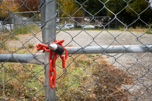 A padlock and red chain on a chain-linked fence around an empty lot in downtown Sacramento photo