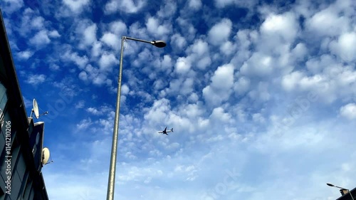 A blue sky with a few clouds and a plane flying in it. The sky is clear and bright, and the plane is flying low