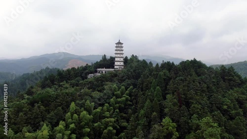 Exploring the serene Wenfeng Pagoda nestled in the lush hills of Jingzhou, Hunan amidst dramatic cloud cover photo