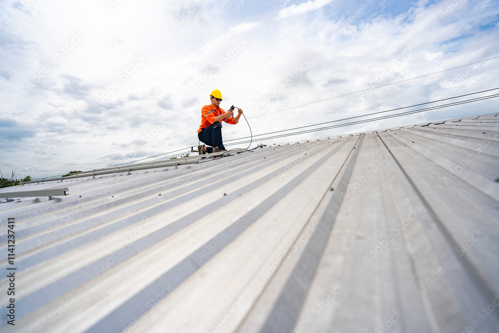 Technician in safety uniform and helmet kneeling on a rooftop, using a drill for precise installation work. A scene highlighting safety, professionalism, and technical expertise in construction. Technician in safety uniform and helmet kneeling on a rooftop, using a drill for precise installation work. A scene highlighting safety, professionalism, and technical expertise in construction.
