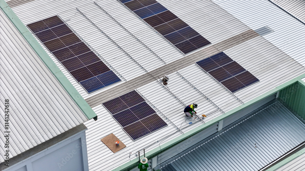 technician in safety gear inspects solar panels on a metal rooftop, holding a tool. The scene emphasizes renewable energy, solar technology, and maintenance of sustainable infrastructure. technician in safety gear inspects solar panels on a metal rooftop, holding a tool. The scene emphasizes renewable energy, solar technology, and maintenance of sustainable infrastructure.