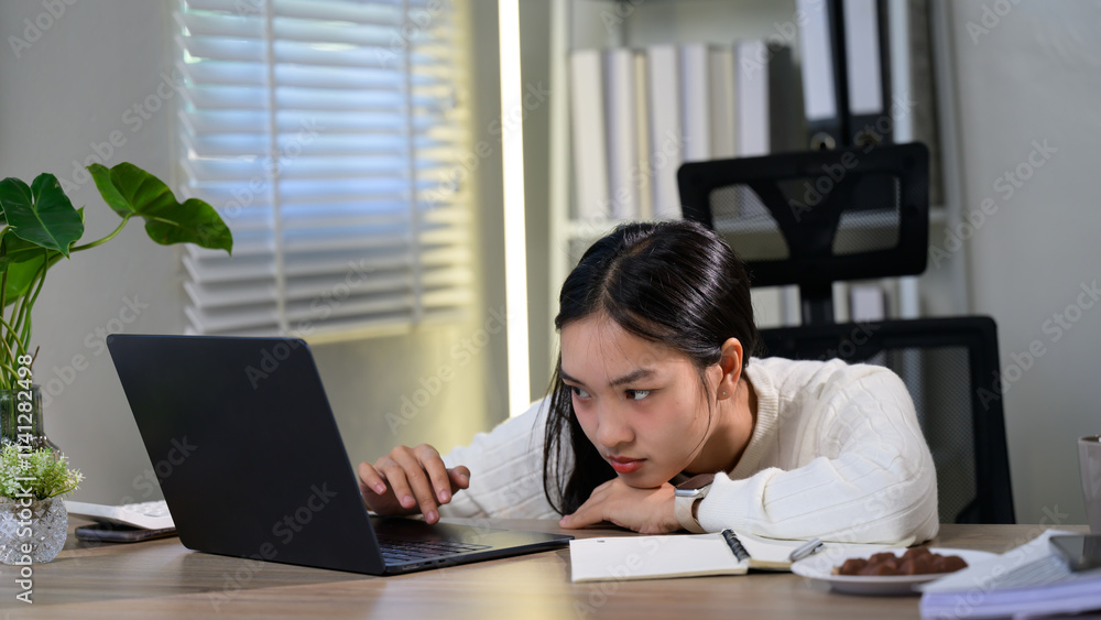 Exhausted asian female entrepreneur suffering from headache and stress while working on a laptop at her home office, overwork and exhaustion concept Exhausted asian female entrepreneur suffering from headache and stress while working on a laptop at her home office, overwork and exhaustion concept