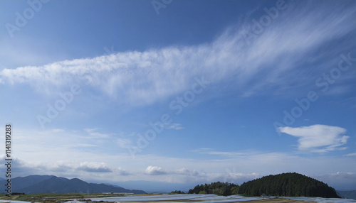 澄み切ったさわやかな日本の冬の青空と長く伸びた雲 海岸や湖の岸に山々の影 正月・新年・アウトドア 朝のイメージ 