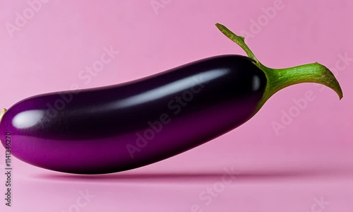 A vibrant eggplant resting against a pink background, showcasing its glossy texture.