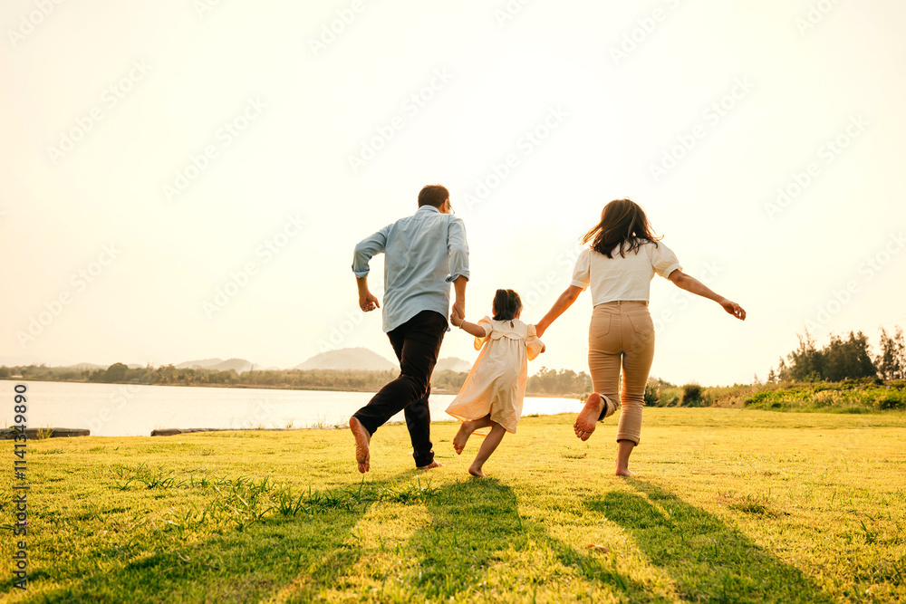 Asian family having fun and enjoying the nature, holding hands running and playing together in a green garden on a sunny day, happy family day Asian family having fun and enjoying the nature, holding hands running and playing together in a green garden on a sunny day, happy family day
