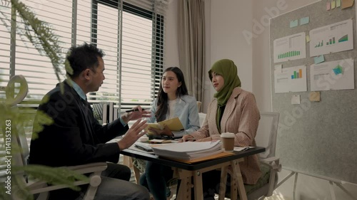 a Muslim female employee wearing a hi jab sits with other employees in an office, the three businessmen were having a meeting to exchange knowledge about Islamic culture