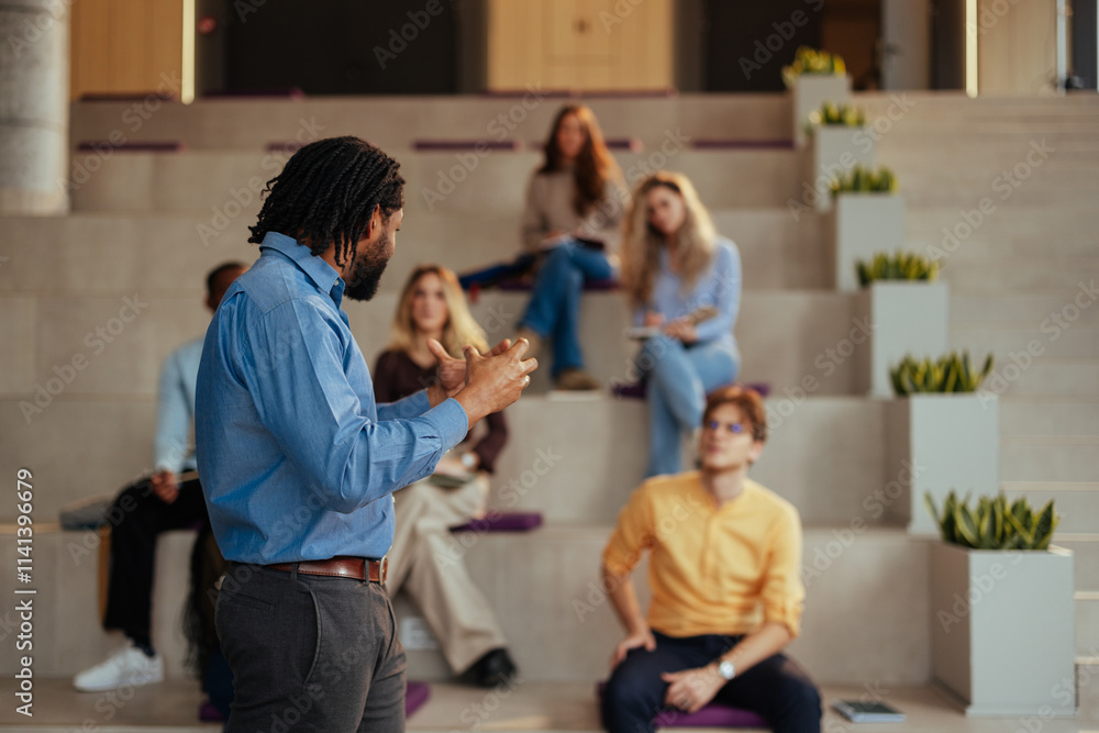 University professor gesturing while giving a lecture to diverse students in modern auditorium University professor gesturing while giving a lecture to diverse students in modern auditorium