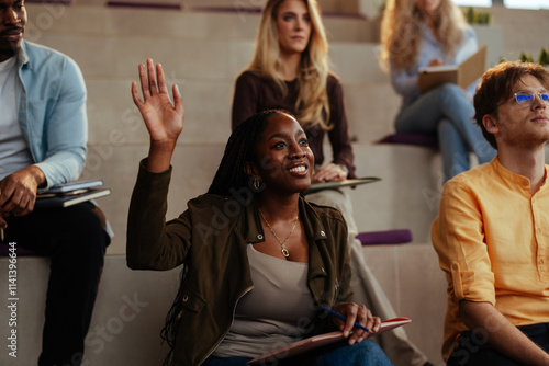 Fotografia University student raising hand in lecture hall asking question