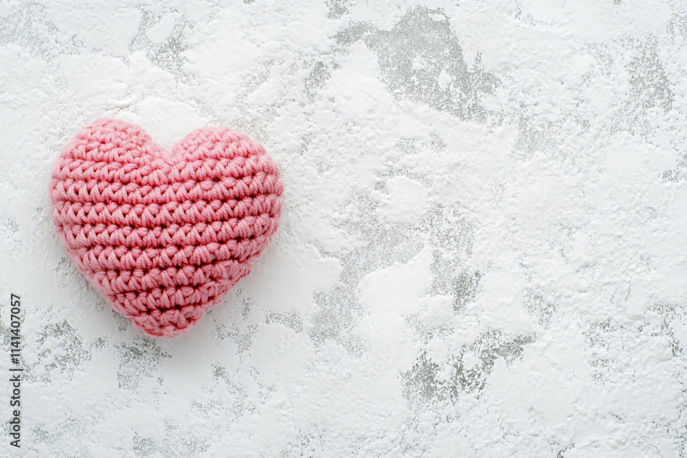 Obraz premium Soft pink crochet heart on textured surface, perfect for Valentine's Day decorations or gifts