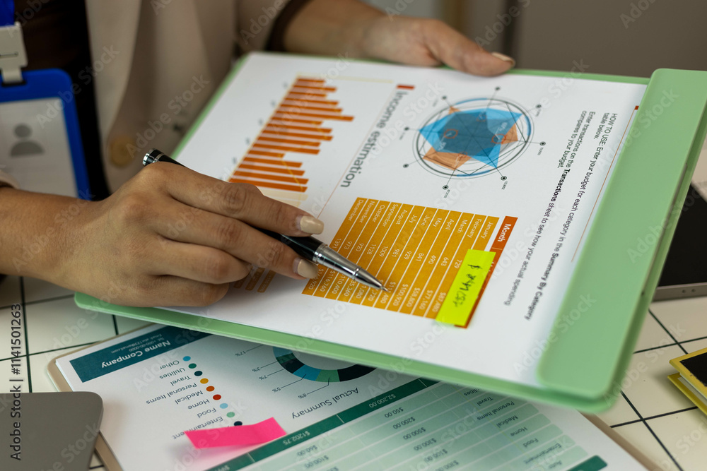 A woman is pointing at a graph on a piece of paper. The graph shows a comparison between two sets of data. The woman is using a pen to highlight the differences between the two sets of data A woman is pointing at a graph on a piece of paper. The graph shows a comparison between two sets of data. The woman is using a pen to highlight the differences between the two sets of data