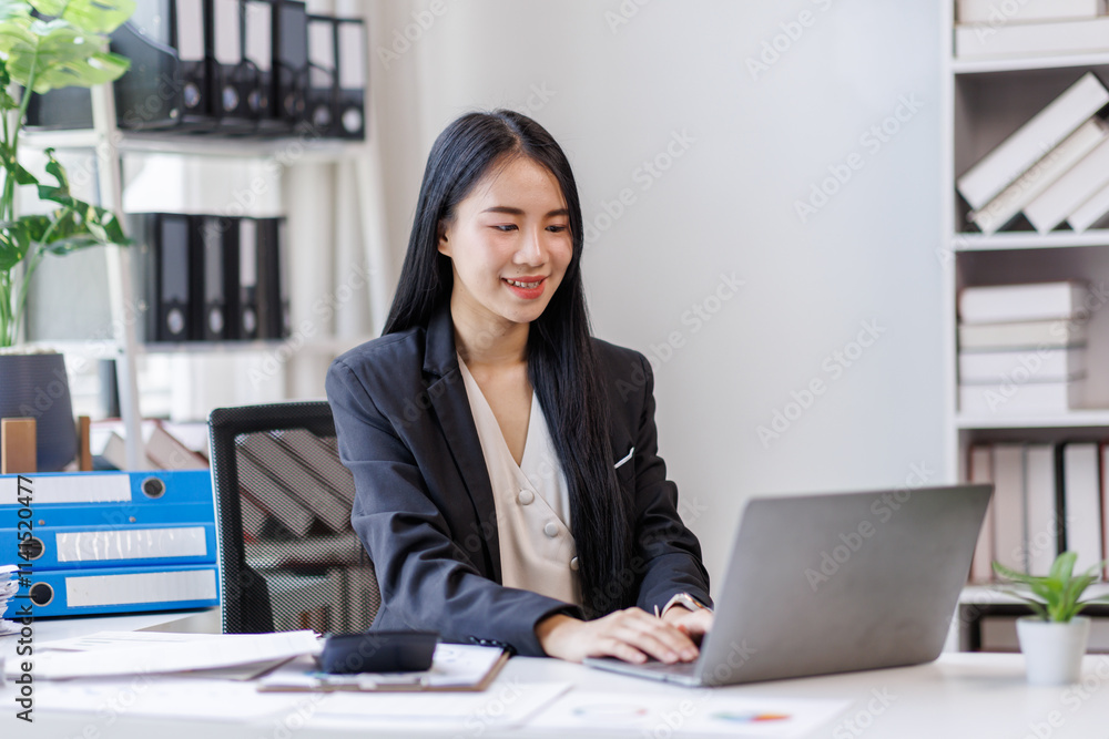 Happy busy young business woman entrepreneur in office using laptop at work, smiling professional asian female company executive manager working looking at computer at workplace. Happy busy young business woman entrepreneur in office using laptop at work, smiling professional asian female company executive manager working looking at computer at workplace.