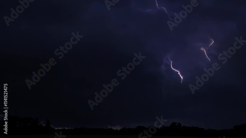 Intense lightning strikes during storm over dark landscape at night