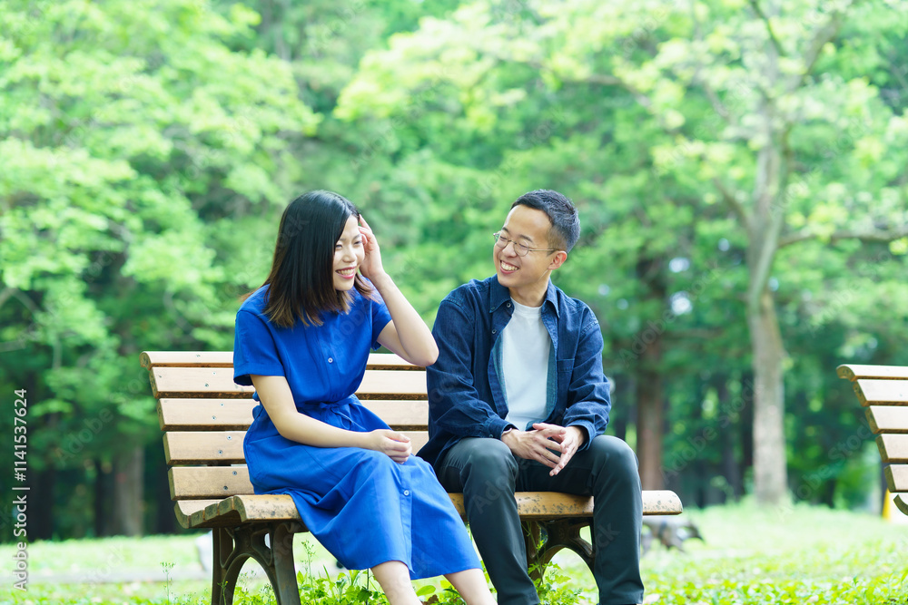 公園のベンチで談笑する若いカップル 公園のベンチで談笑する若いカップル