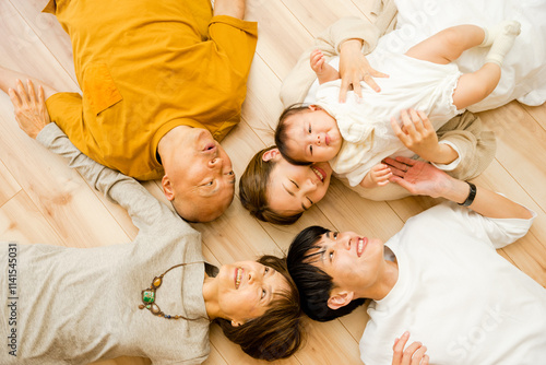 床に並んで上向きで寝そべる赤ちゃんと両親と祖父母の3世代の家族5人 photo