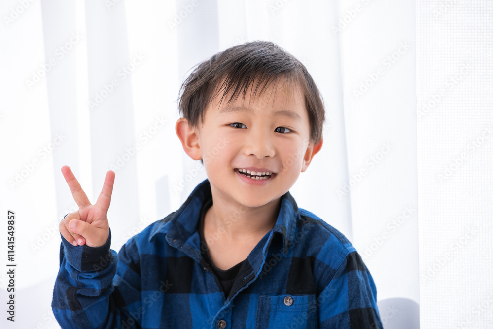 ピースサインをする笑顔の男の子　５歳