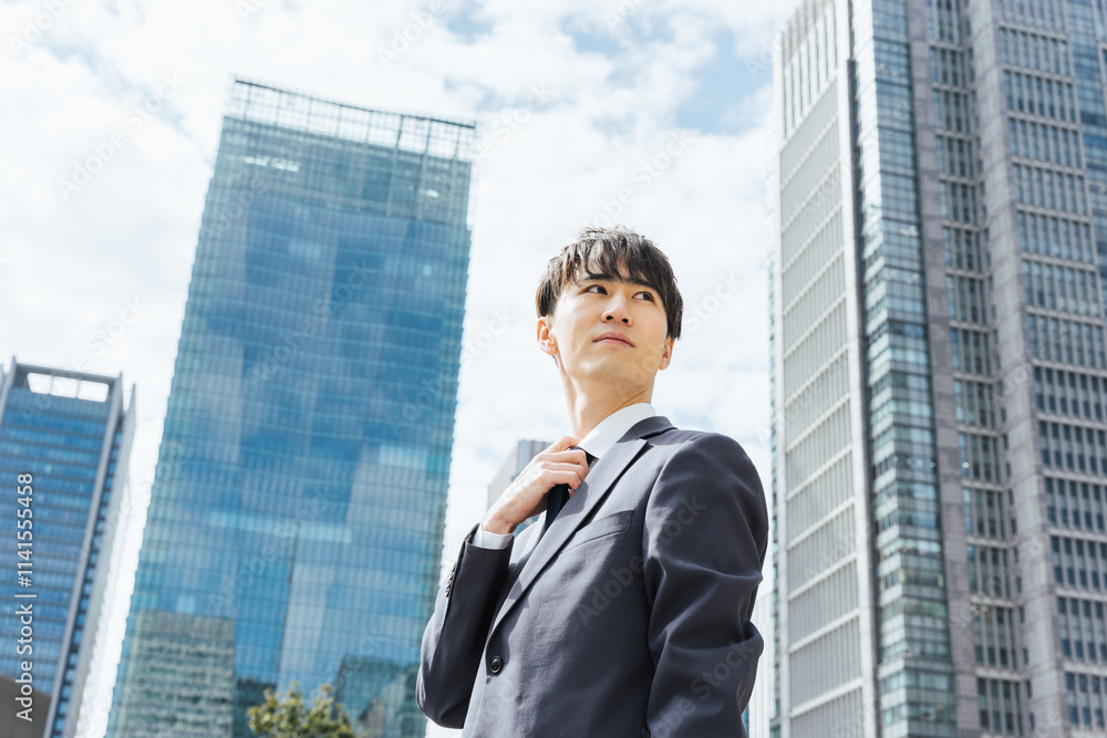 ビジネス街でクールに振り向く20代のスーツ姿のビジネスマンの男性 ビジネス街でクールに振り向く20代のスーツ姿のビジネスマンの男性
