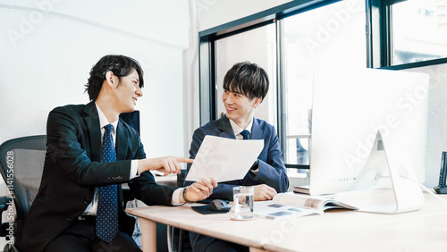 Tapety artystyczne オフィスの社内で社員同士でアイデアを出し合う20代から30代の2人の若手社員の男性