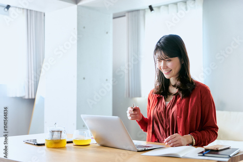 一人暮らしの部屋で大学や学校のオンライン授業をノートパソコンで受講する20代から30代の女性の学生 photo