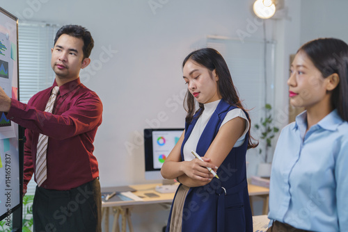 Asian business team of men and women pointing at documents, graphs, charts on board. Brainstorming and explaining. Planning statistics on organizational chart board in company. Colleague concept.