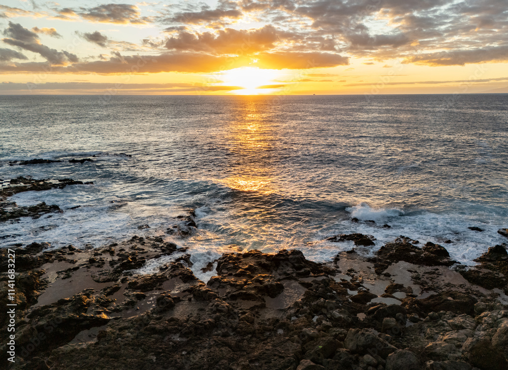 Golden sunset in south of Tenerife, Atlantic ocean waves crash on the rocky beach, horizon over water Golden sunset in south of Tenerife, Atlantic ocean waves crash on the rocky beach, horizon over water
