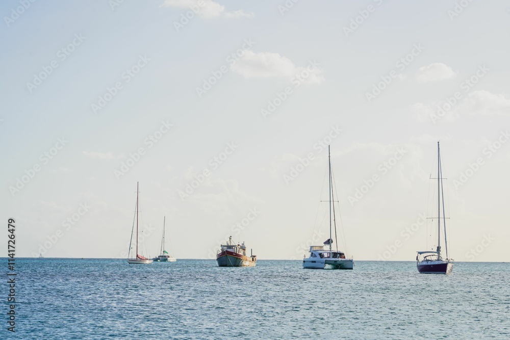 Obraz premium Sailboats anchored in a calm sea under a clear sky.