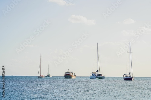 Sailboats anchored in a calm sea under a clear sky.