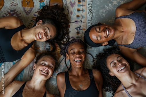 A group of women are laying on a rug, smiling and laughing together