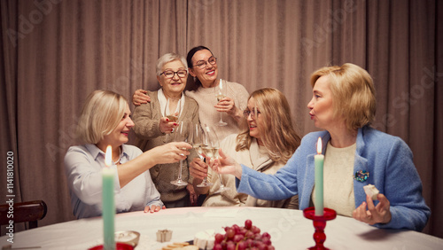 Photography Happy laughing women, five friends cheerfully spending warm time at home, in warmly-lit living room, talking and drinking wine