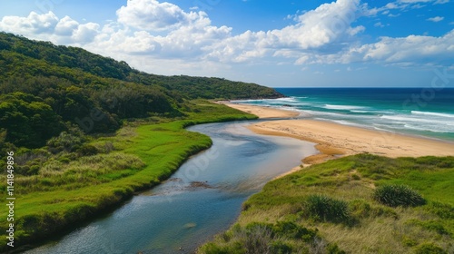 Scenic view of a tranquil river winding through lush greenery toward the ocean under a bright blue sky with fluffy clouds