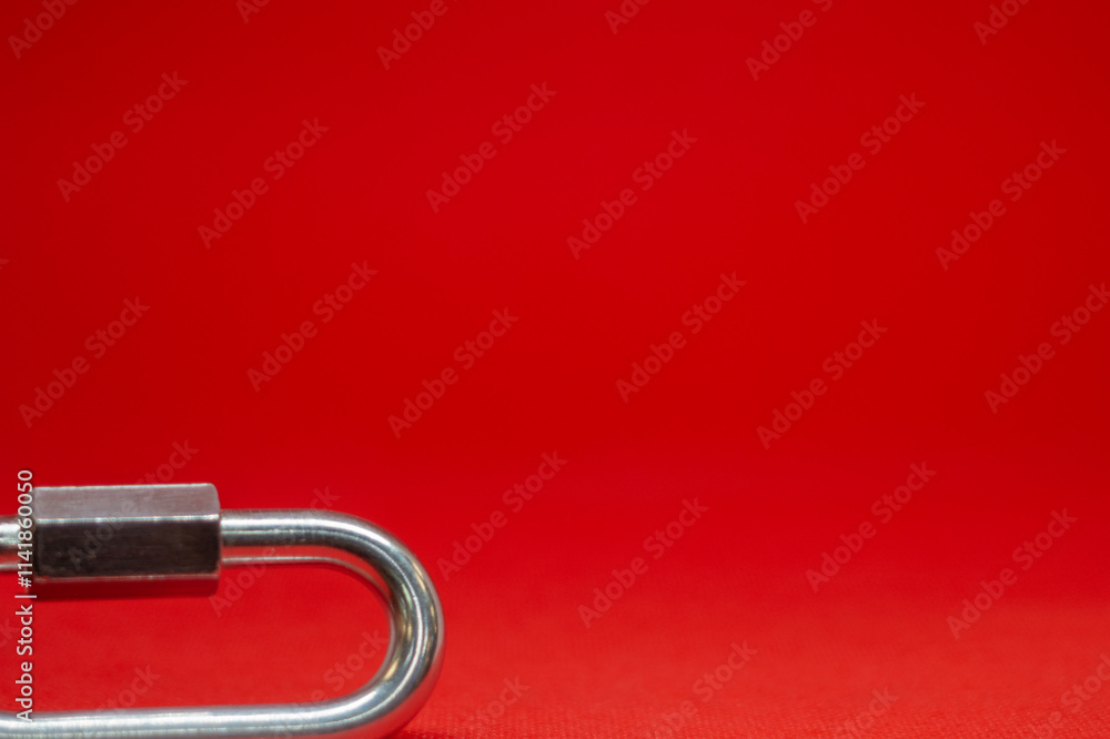 Climbing carabiner on a red background close-up, selective focus Climbing carabiner on a red background close-up, selective focus