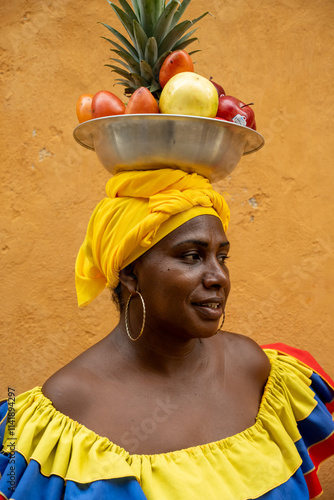 A Close-Up Of A Palenquera Woman In A Traditional Yellow Dress Balancing A Fruit Basket On Her Head.