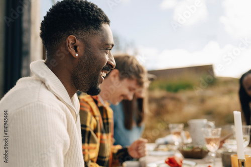 Side view of happy man having dinner with friends at outdoor setting photo