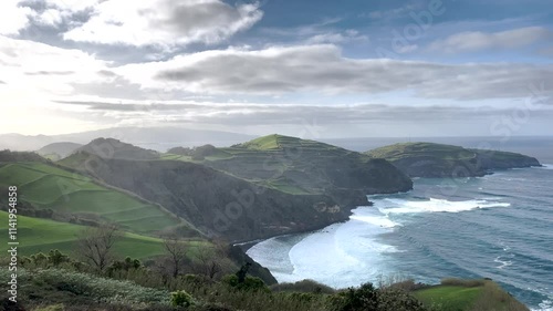 Aerial view of waves crashing against the shore in a tropical paradise, surrounded by lush green trees, creating a serene coastal landscape. photo