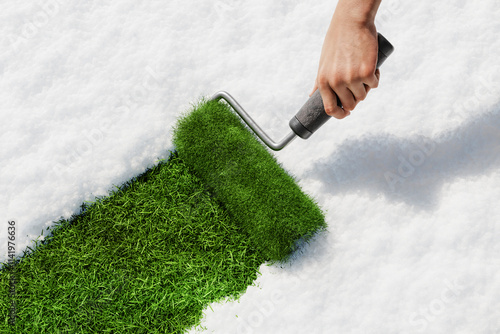 Hand painting green grass over white snow with paint roller in springtime