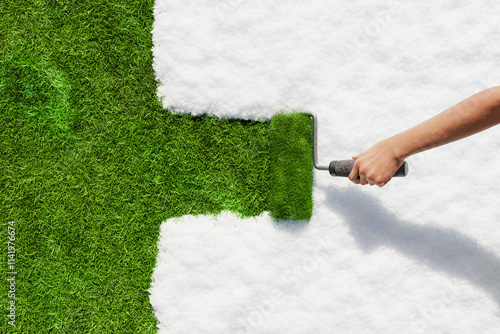 Hand painting green grass over white snow with paint roller, springtime renewal
