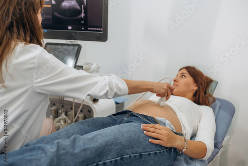 Monitor with graphical representation of scan. Pregnant woman undergoing ultrasound test photo