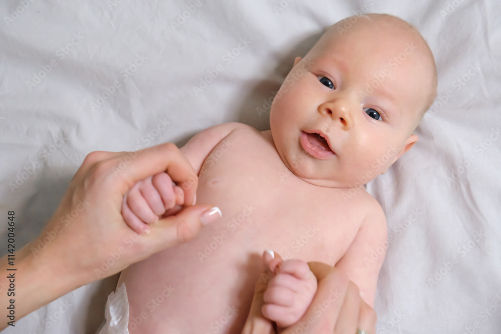 Joyful Two-Month-Old Baby Boy Holding Mom's Hands on a Light Background. Selective Focus Joyful Two-Month-Old Baby Boy Holding Mom's Hands on a Light Background. Selective Focus