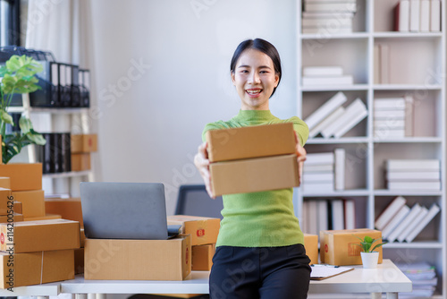 Happy young asian woman SME startup small business freelance work on parcel box and laptop computer Prepare to deliver items to customers , Online marketing packing box delivery SME e-commerce concept