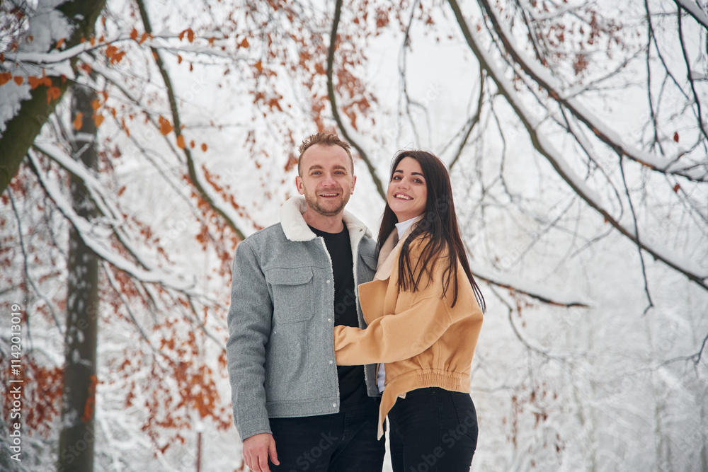 Beautiful couple are standing together on the snowy field of forest Beautiful couple are standing together on the snowy field of forest