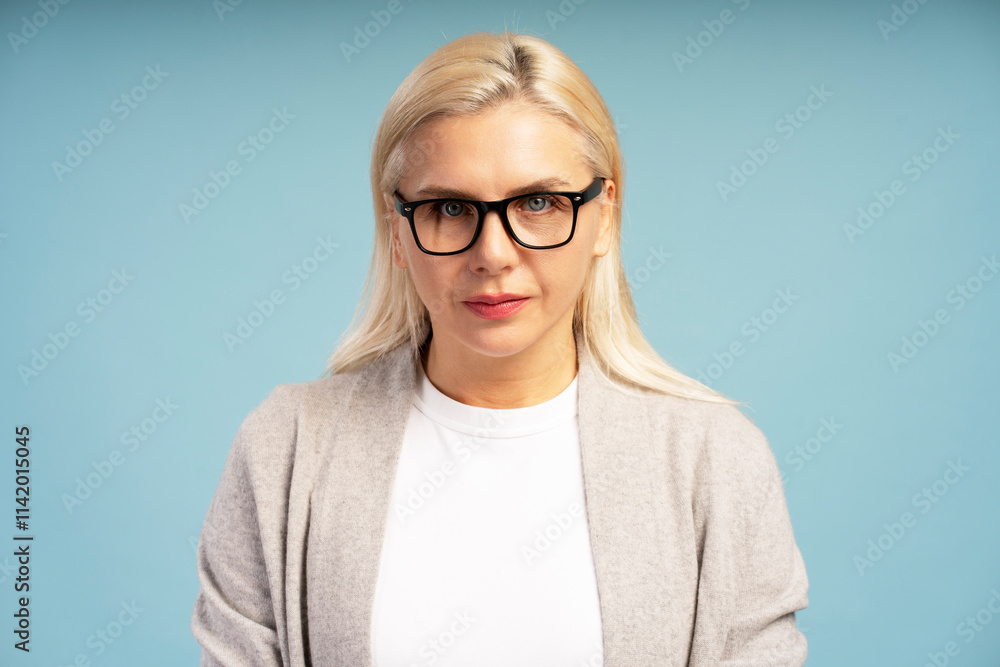 Serious blond woman wearing glasses posing on blue background Serious blond woman wearing glasses posing on blue background