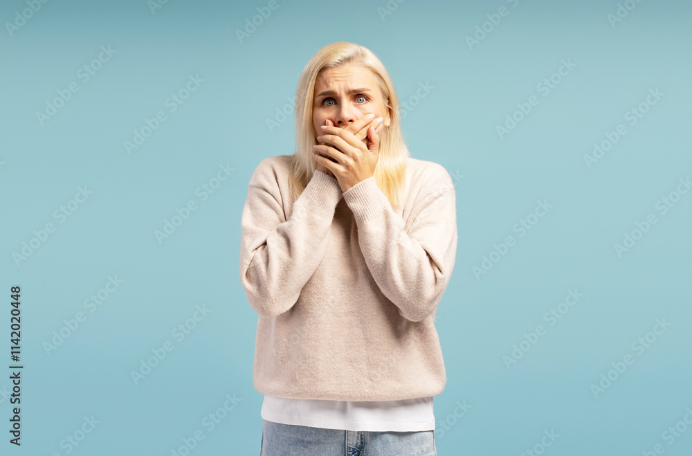 Shocked woman covering her mouth with hands on blue background Shocked woman covering her mouth with hands on blue background