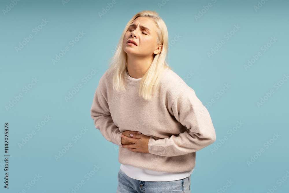 Woman suffering from strong stomach ache on blue background Woman suffering from strong stomach ache on blue background