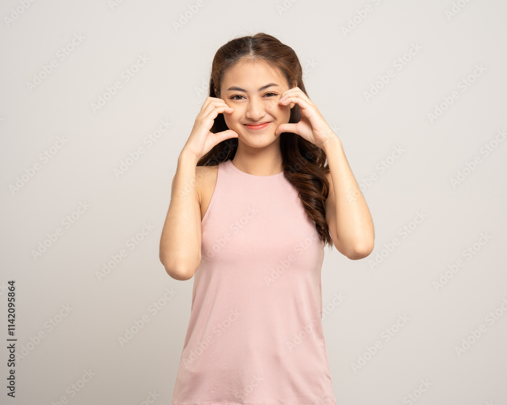 Pretty Young beautiful Asian woman standing and smiling showing mini heart sign on isolated white background. Lovely Latin female wearing pink shirt feeling surprised and happy. Pretty Young beautiful Asian woman standing and smiling showing mini heart sign on isolated white background. Lovely Latin female wearing pink shirt feeling surprised and happy.