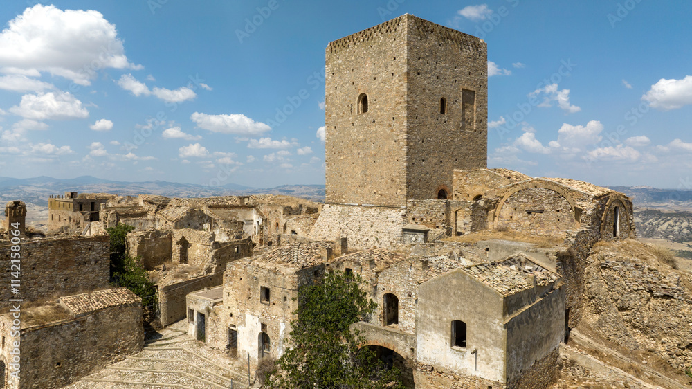 Aerial view of the medieval tower located in Craco, a ghost town in province of Matera, Basilicata, Italy. The historic center was depopulated due to a landslide and has become a tourist destination. Aerial view of the medieval tower located in Craco, a ghost town in province of Matera, Basilicata, Italy. The historic center was depopulated due to a landslide and has become a tourist destination.