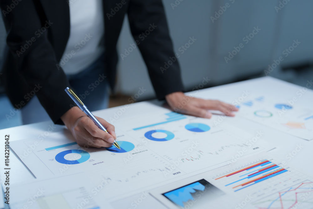 Businesswoman analyzing investment charts and graphs with a pen, working on financial documents, and planning strategies for business growth and market analysis Businesswoman analyzing investment charts and graphs with a pen, working on financial documents, and planning strategies for business growth and market analysis