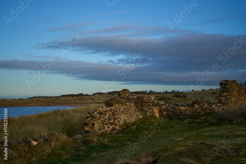 Gullane, East Lothian, Scotland. Serene scene: green grass, stone wall, blue sky with fluffy clouds.